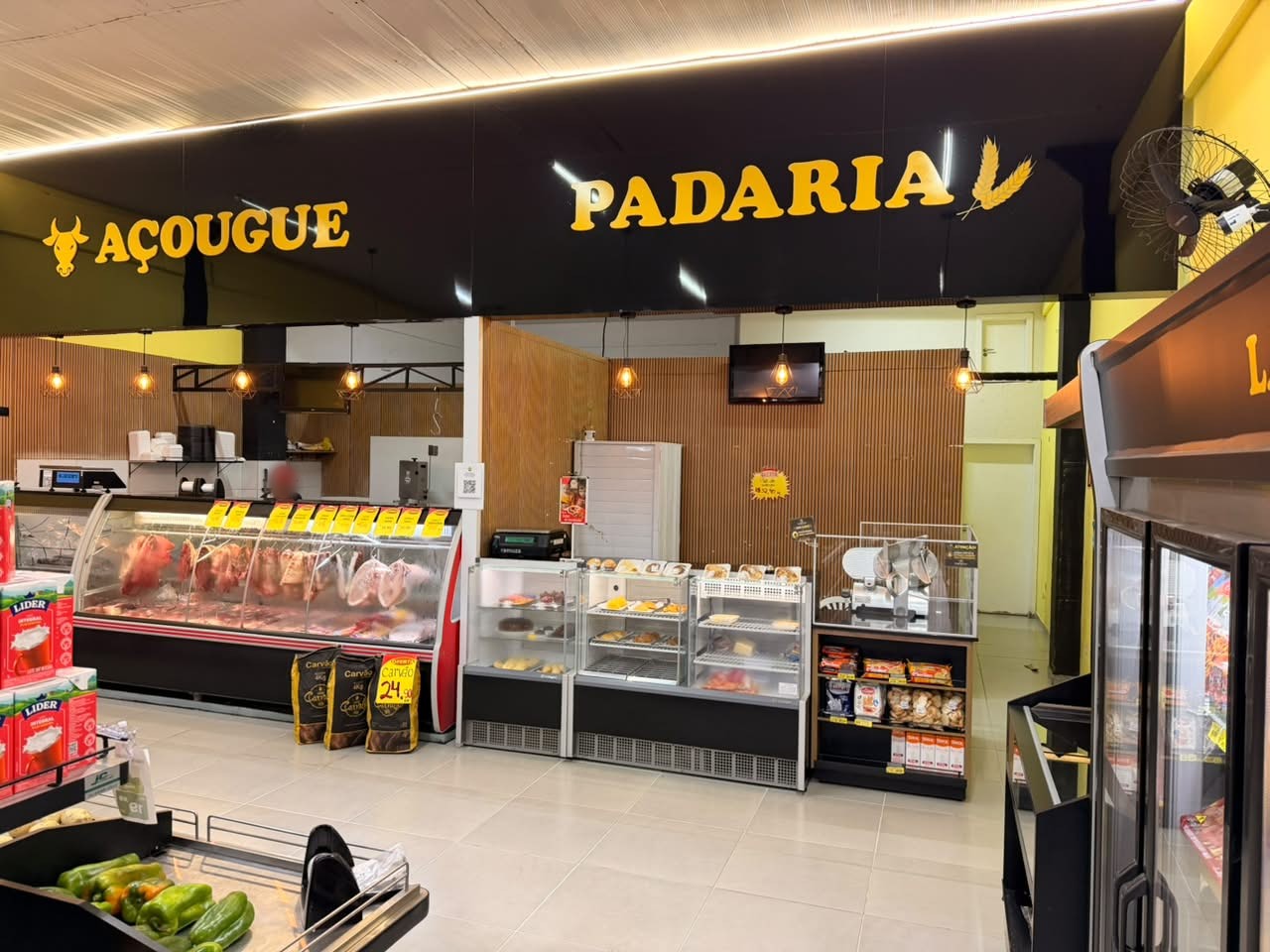 Balcão refrigerado do açougue e vitrines da padaria, sob os letreiros dourados