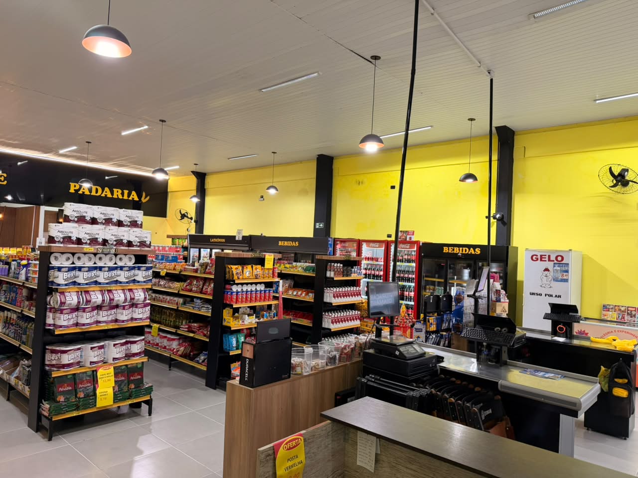 Frente de caixa com checkouts e área de bebidas ao fundo